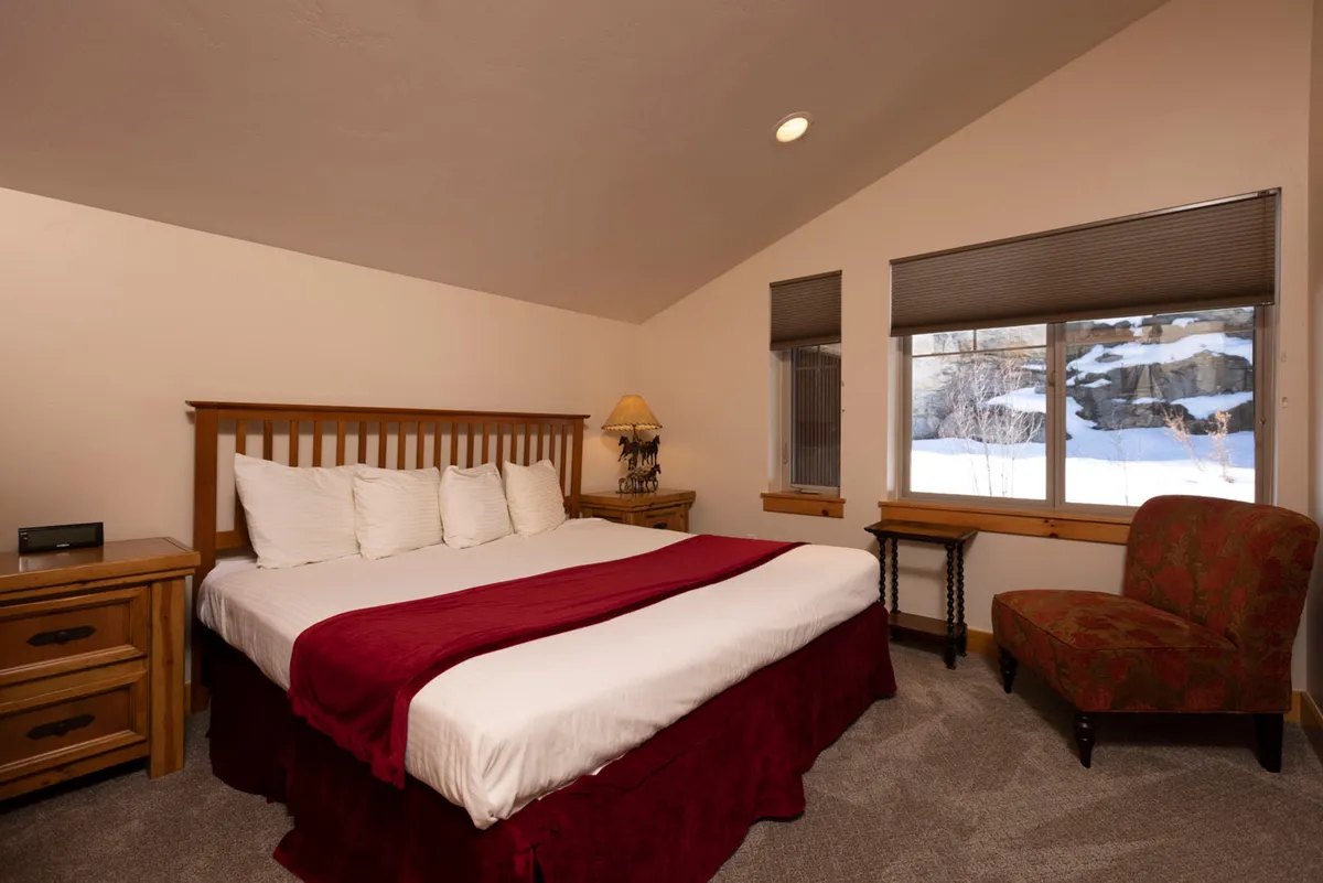 A bright and inviting bedroom featuring a comfortable bed positioned next to a window with sunlight streaming in. A cozy chair is placed nearby, ideal for reading or relaxing. The overall ambiance is restful and serene, emphasizing private sanctuary and comfort.